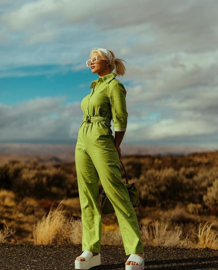 Photo of Cirena Wilson in a green jumpsuit accompanied by a pair of thick soled white slippers and white framed spectacles.